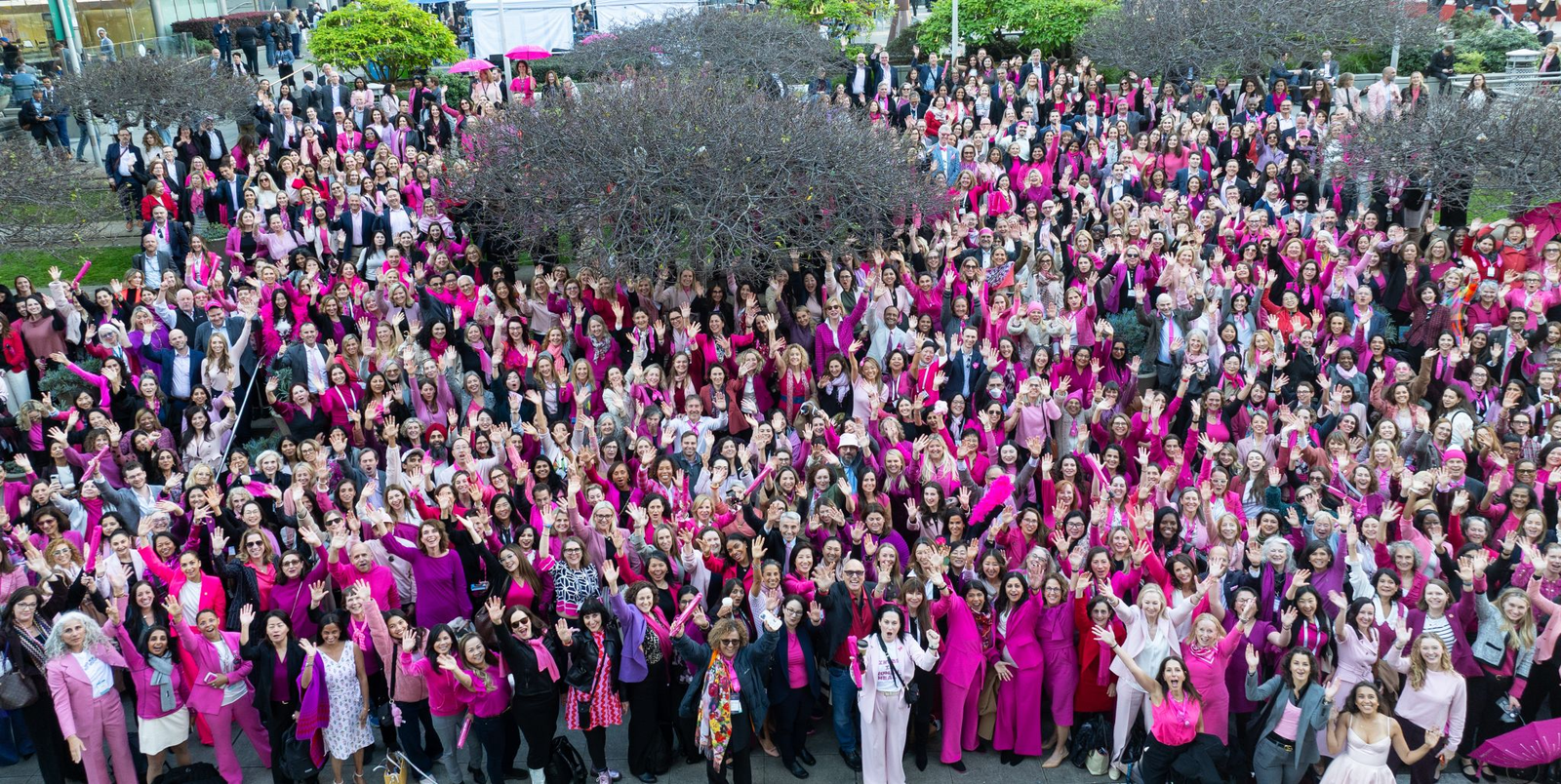 Aerial drone photo showing 950 attendees in coordinated pink attire gathered in a downtown San Francisco plaza for a corporate group photo