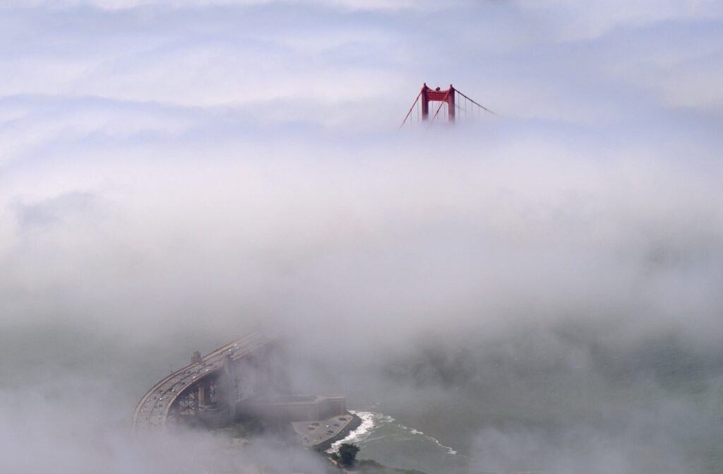 Golden Gate Bridge towers emerging through marine fog — aerial photograph by San Francisco aerial photographer Josh Edelson