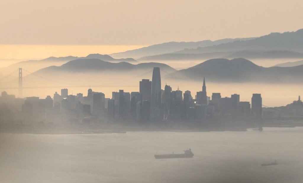 San Francisco Bay Area aerial panorama with marine fog rolling across the skyline — editorial aerial photography by Josh Edelson