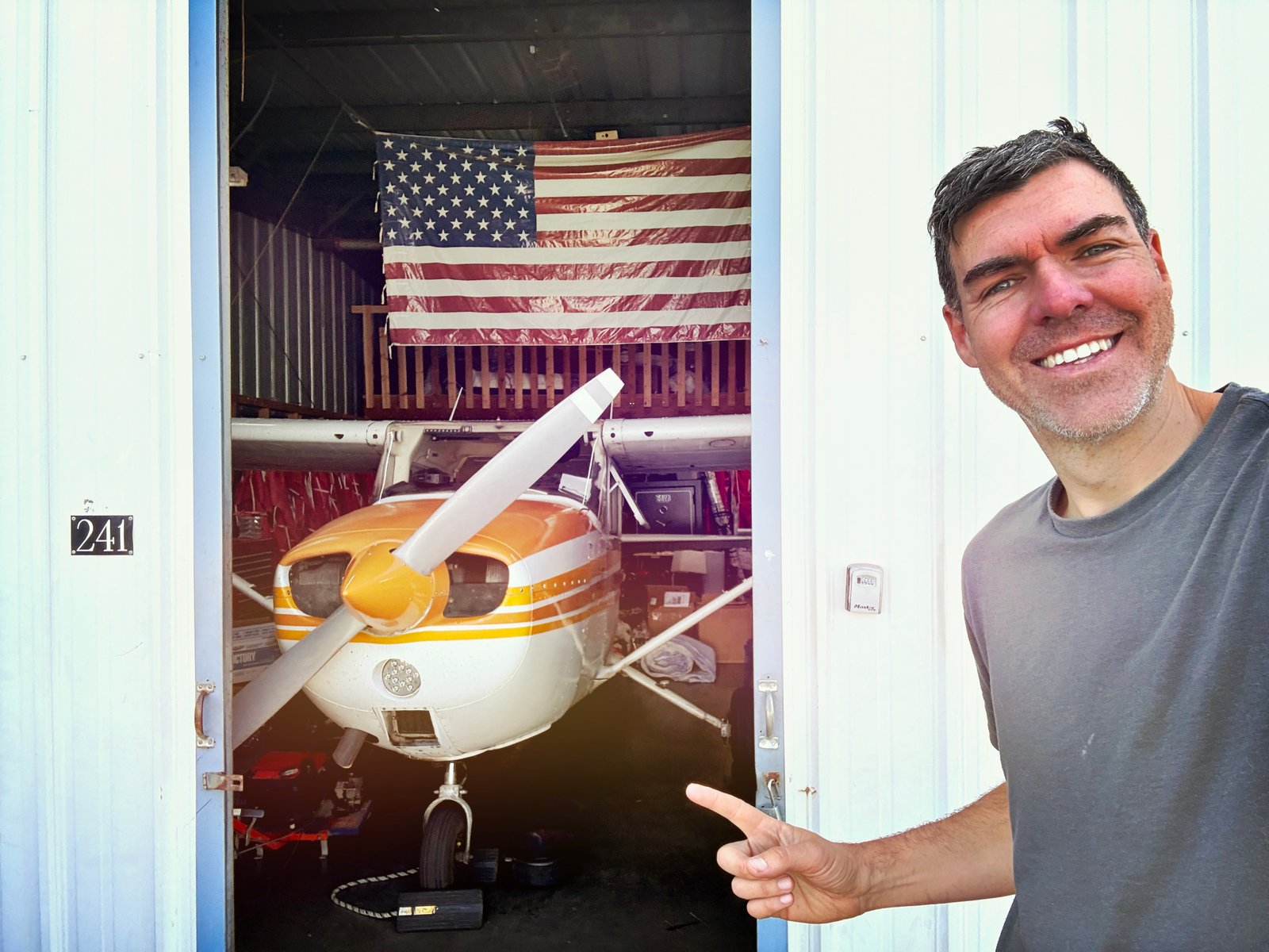 Josh Edelson standing next to his Cessna aircraft in hangar 241, used for aerial photography assignments over Silicon Valley and San Francisco