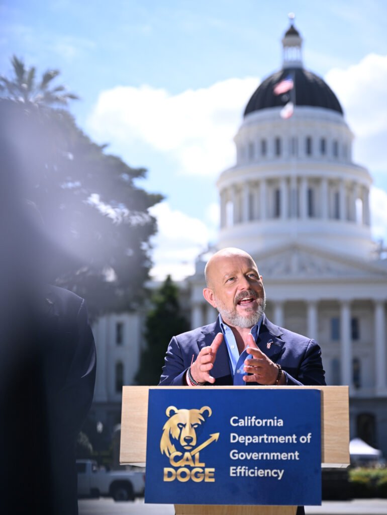 Steve Hilton speaking at a podium during a press conference outside the California State Capitol