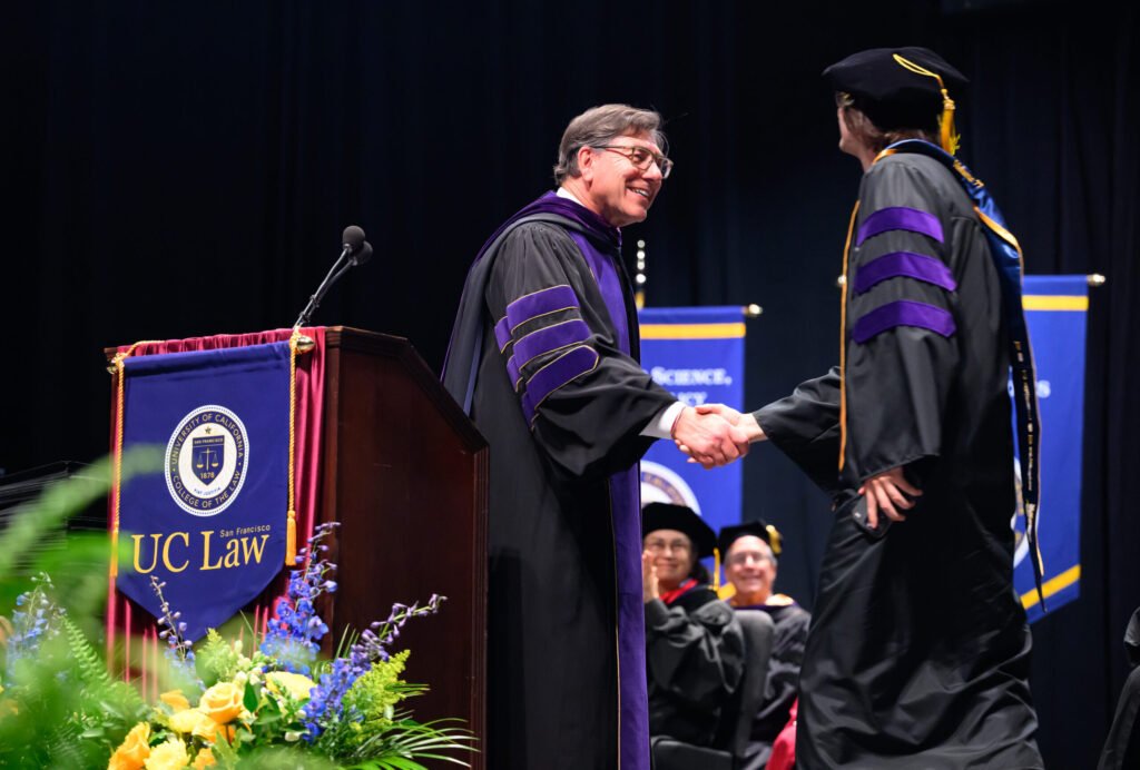 UC Law San Francisco dean presents diploma to graduate on stage during commencement ceremony — photo by Josh Edelson
