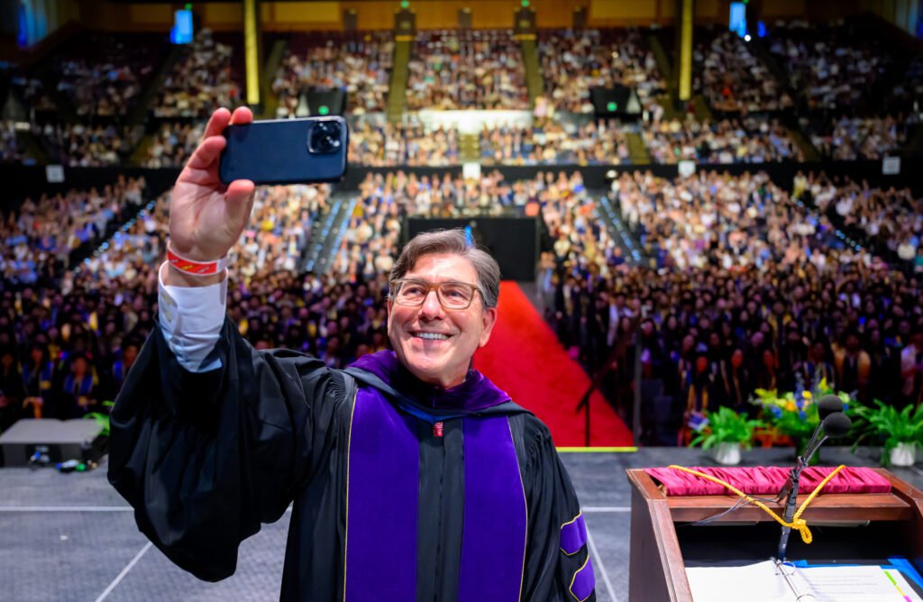 UC Law San Francisco dean takes a selfie with the entire packed arena of graduates at the 2026 commencement ceremony — photo by Josh Edelson