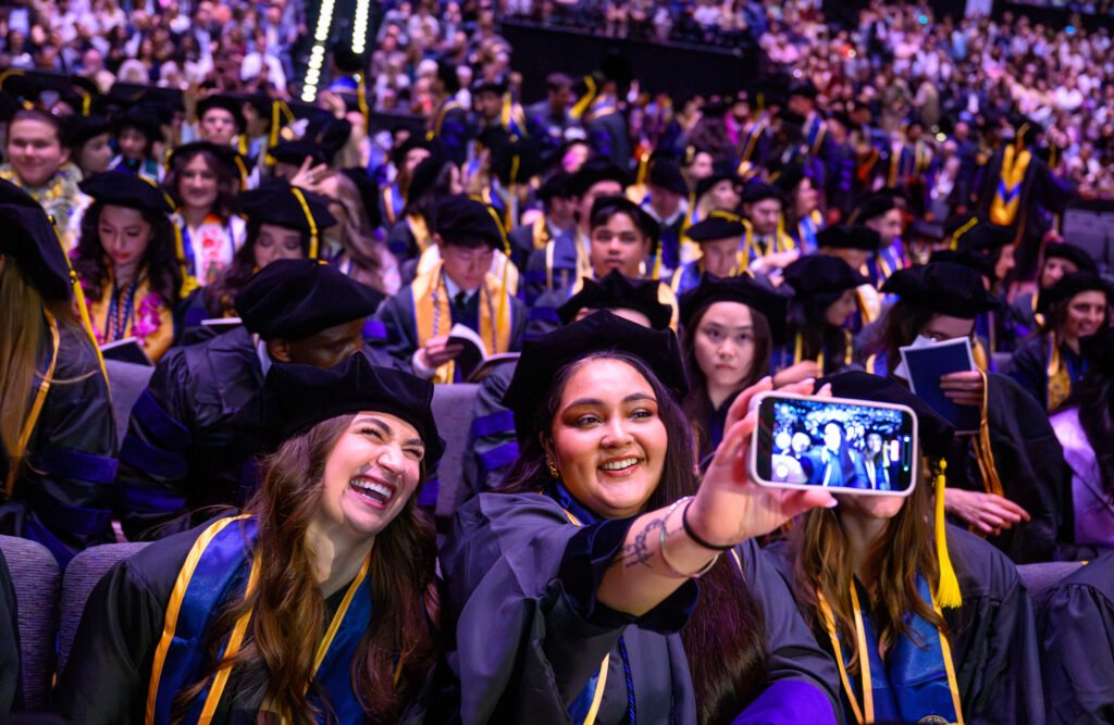 UC Law San Francisco graduates take a selfie during the 2026 commencement ceremony — photo by Josh Edelson