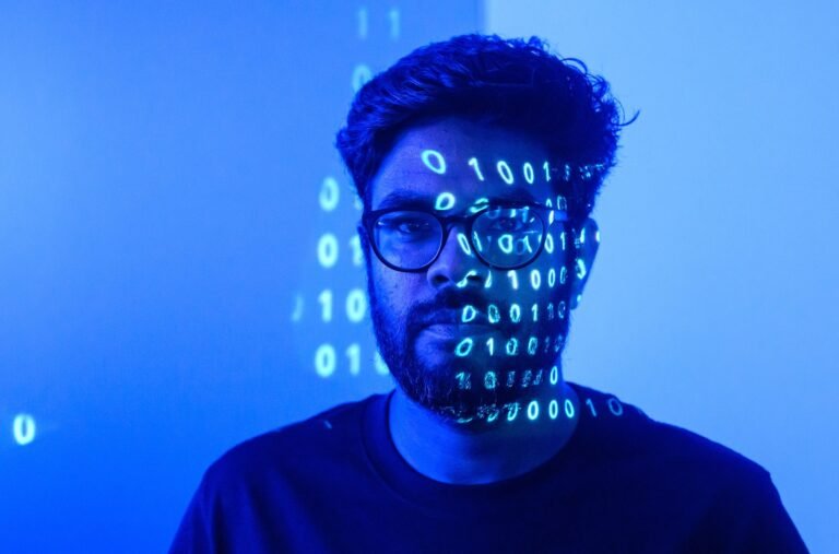 Luma AI CEO Amit Jain lit in blue with projected ones and zeros across his face, the lead portrait for the Los Angeles Times shot in Palo Alto