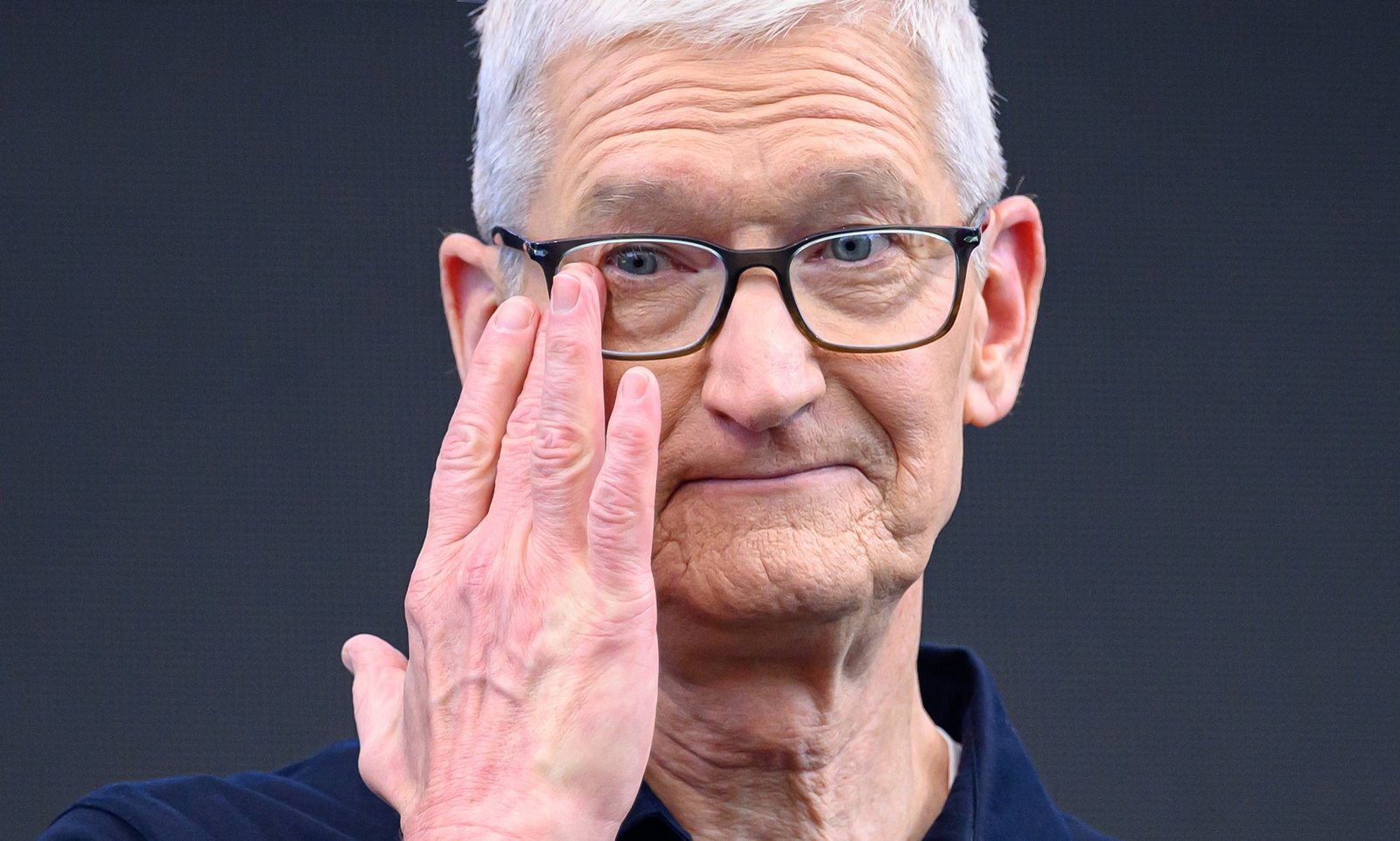 Tight close-up of Apple CEO Tim Cook wiping away a tear, eyes glistening, during his final WWDC keynote
