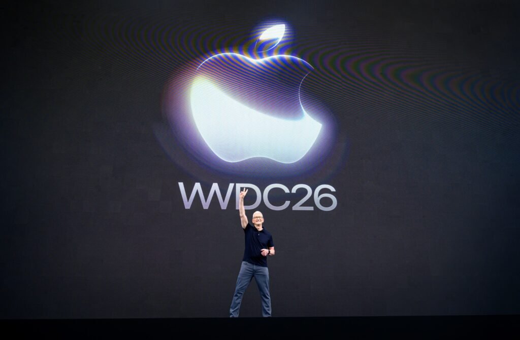 Apple CEO Tim Cook on stage with his arm raised beneath the Apple logo and WWDC26 sign at the 2026 Worldwide Developers Conference keynote at Apple Park