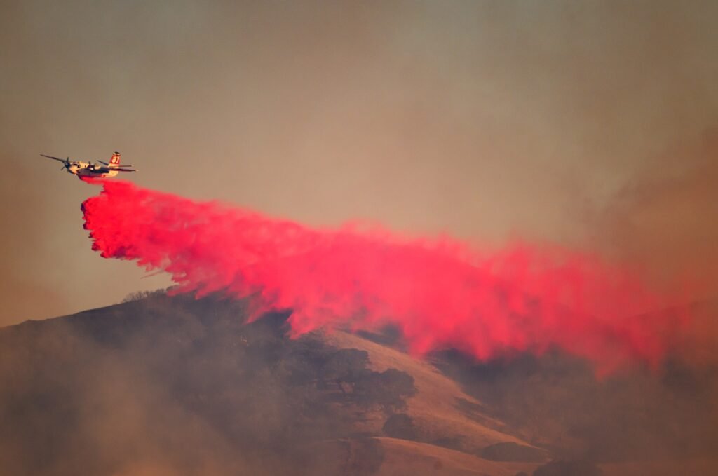 An air tanker drops red fire retardant along a hillside at the Little Fire in Pleasanton, California