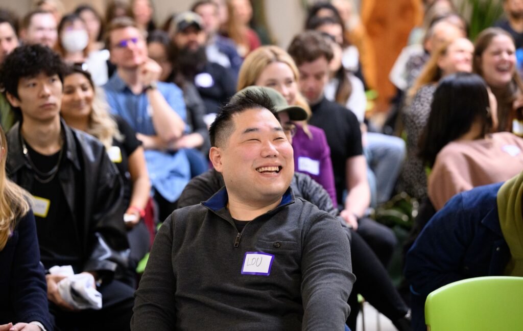An engaged attendee laughing during a corporate event talk, event photography by Josh Edelson