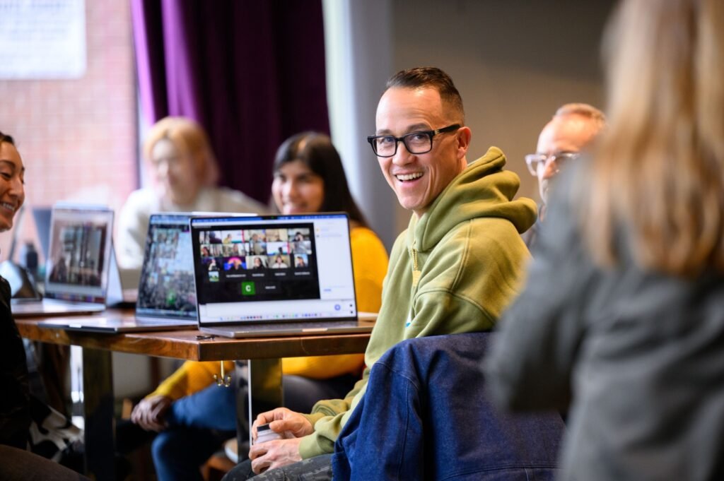 An attendee at a hybrid corporate event with a video call on screen, event photography by Josh Edelson