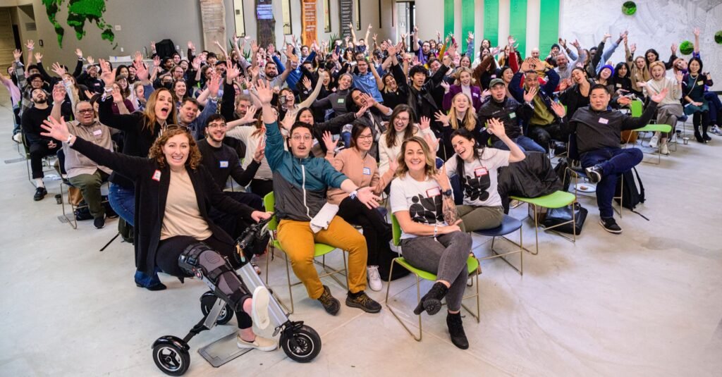 A large group company photo with the whole team cheering at a corporate event, by Josh Edelson