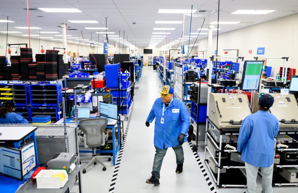 Wide view of a technology manufacturing floor with technicians at workstations, corporate environmental and lifestyle photography by Josh Edelson