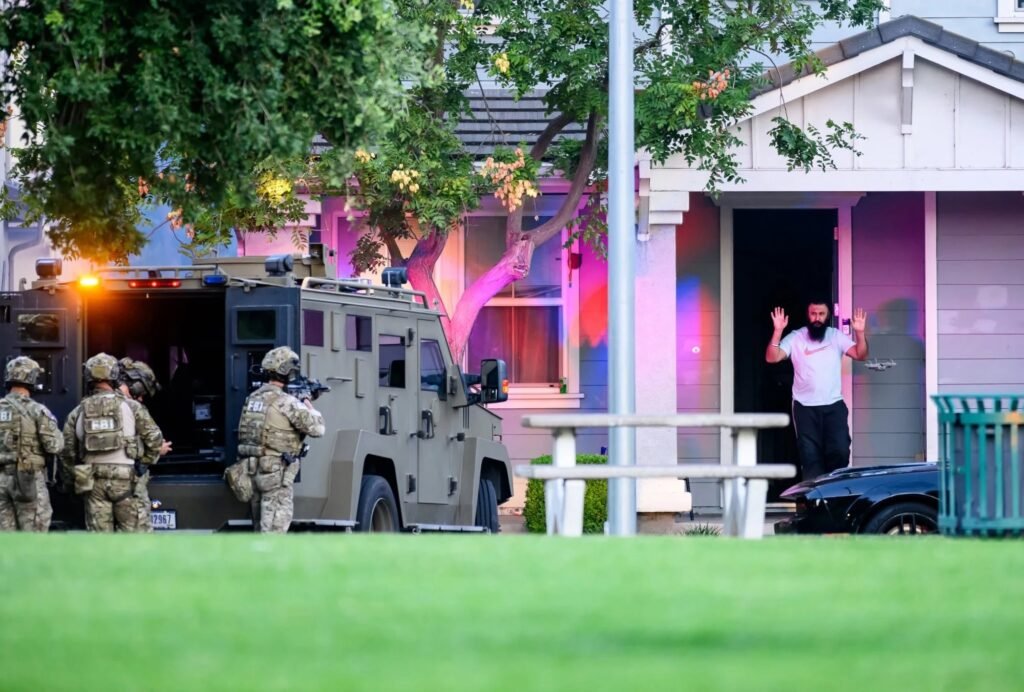 FBI SWAT team and armored vehicle as a suspect surrenders with his hands up during a federal raid, by Josh Edelson