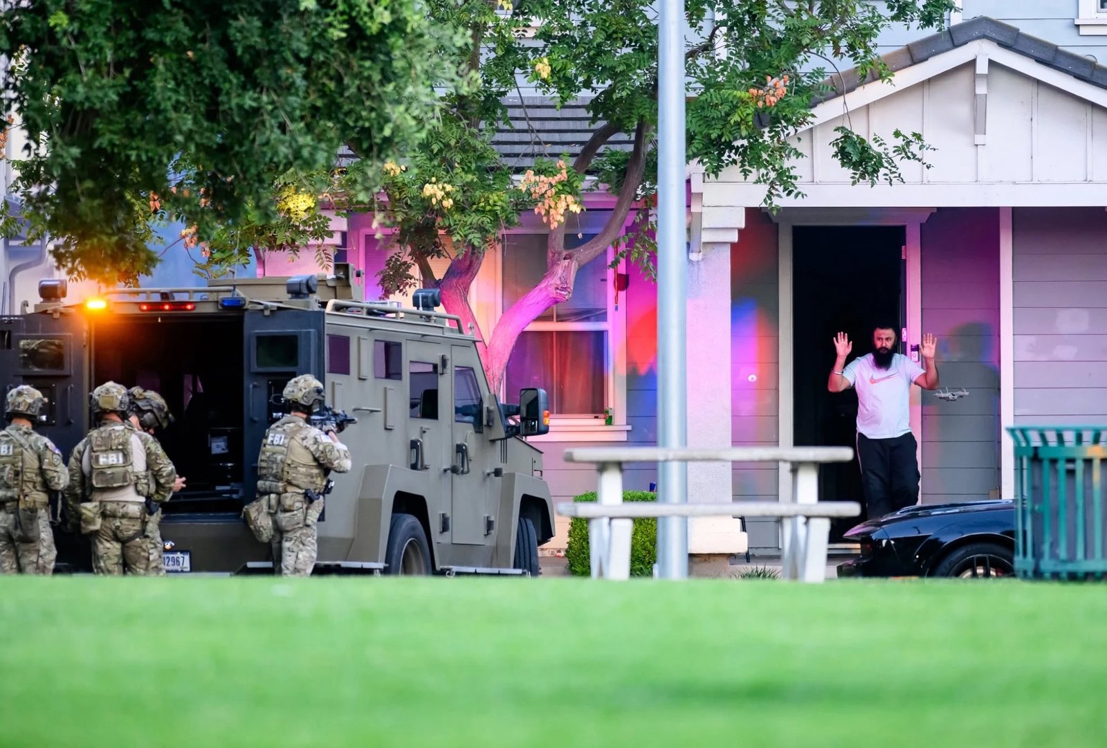 A suspect steps out with his hands raised.