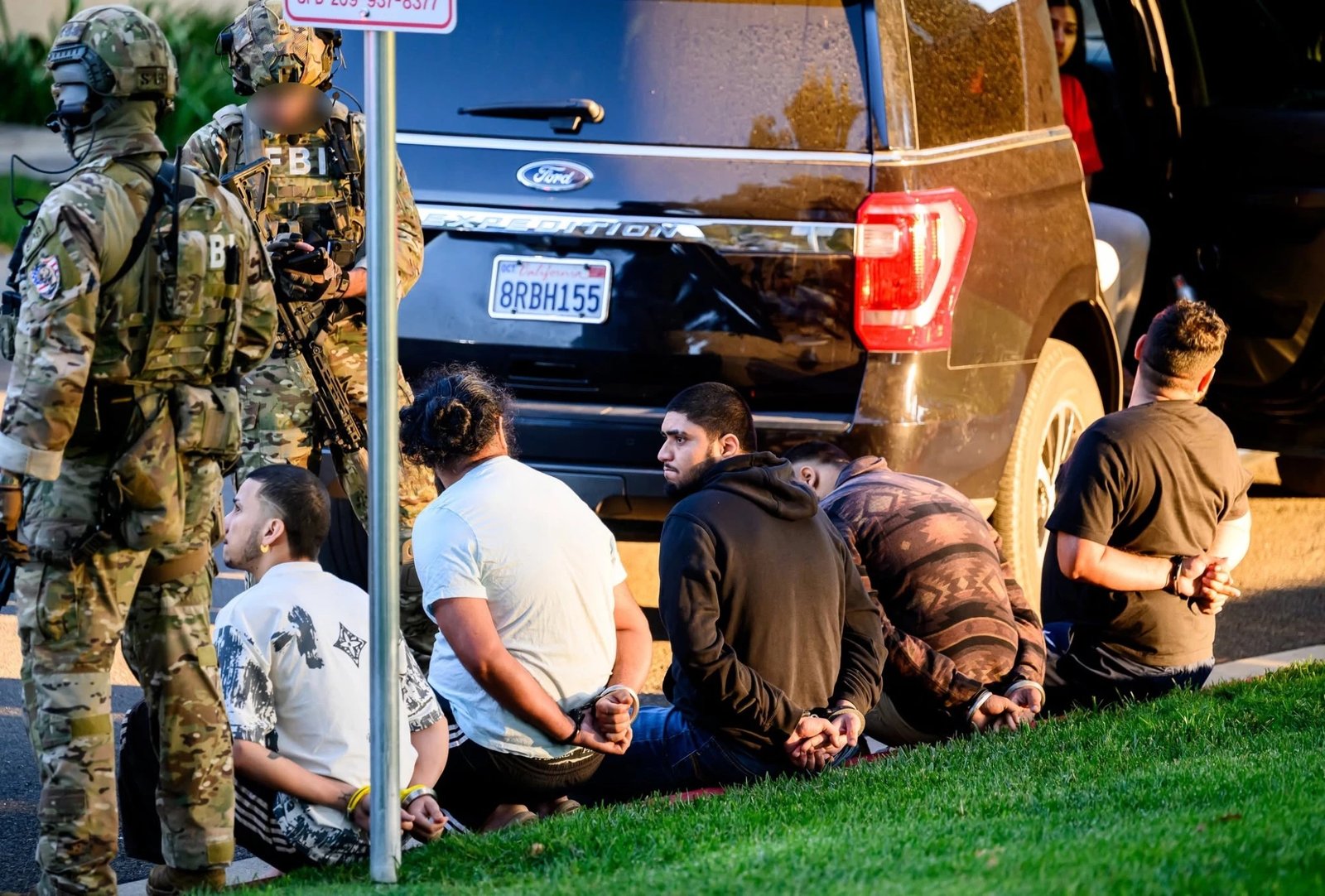Five men sit handcuffed on the ground after the raid.