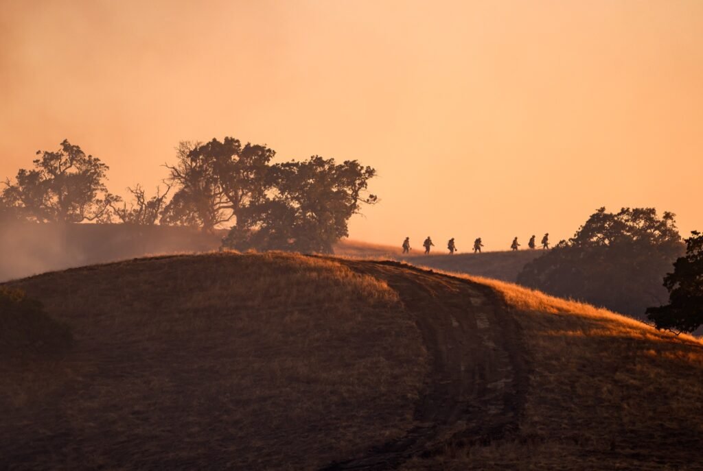 A hand crew of firefighters walks a ridgeline through smoke at the Little Fire in Pleasanton, California