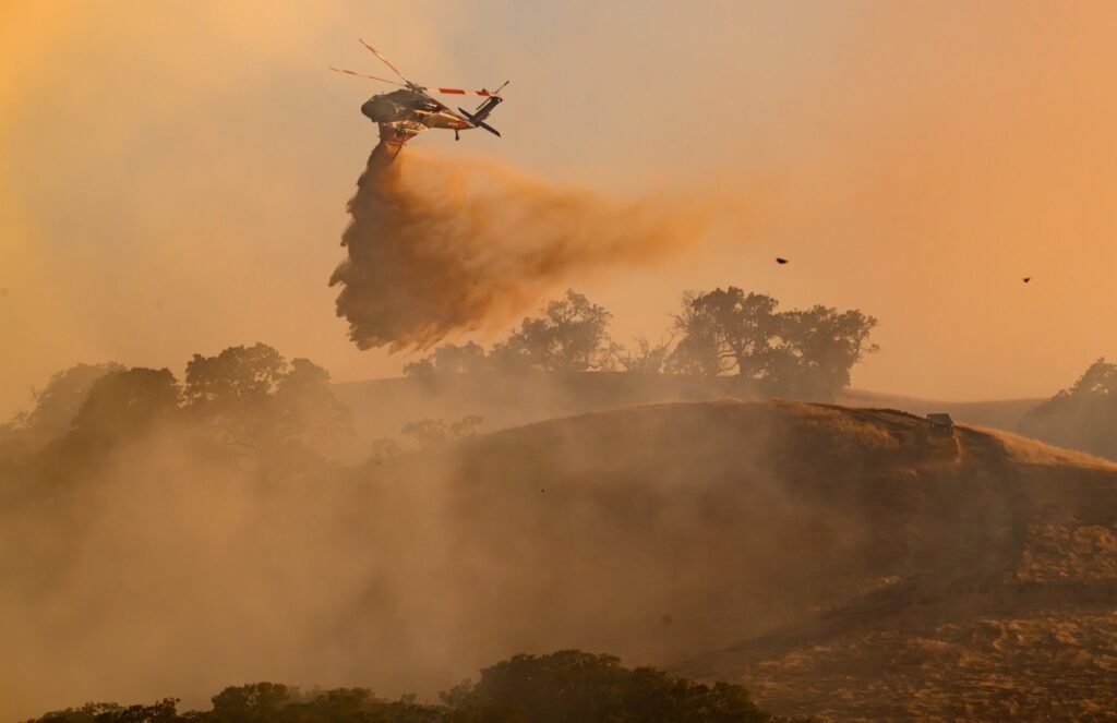 A helicopter makes a water drop over the hills at the Little Fire in Pleasanton, California