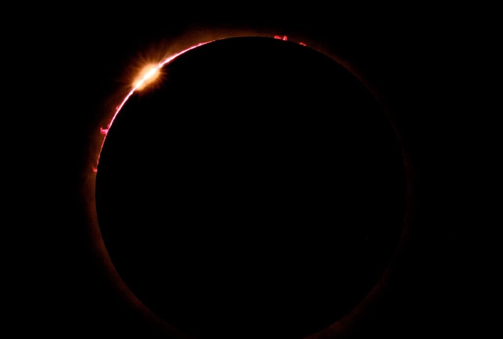 The diamond ring and red solar prominences during a total solar eclipse, photographed by Josh Edelson