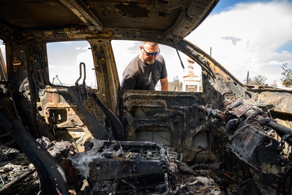Resident Luke Opperman views his burned work truck as his home smolders during the Hawk Fire in Reno, Nevada, August 24, 2026. (Josh Edelson / AFP)