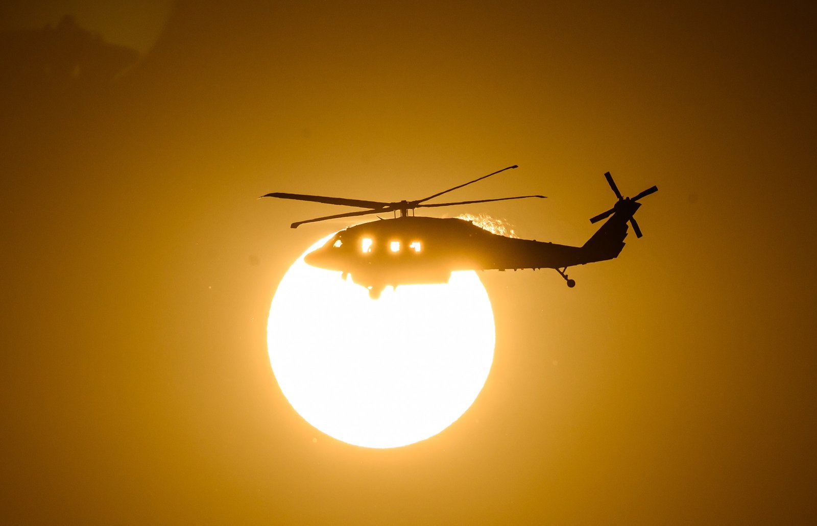 A CalFire helicopter crosses the sun on its way to make a water drop during the Little Fire in Pleasanton, California on July 21, 2026. (Photo by Josh Edelson / AFP)