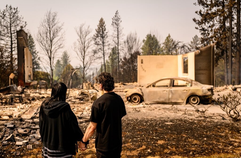 Shyla Zavala and Jin Brooks view their burned home during the Old Trails Fire in Spokane, Washington, August 4, 2026. (Josh Edelson / AFP)