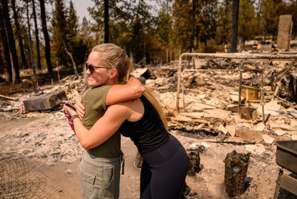 Kimber Renz hugs her mother Kristen Renz at her burned home during the Old Trails Fire in Spokane, Washington, August 4, 2026. (Josh Edelson / AFP)
