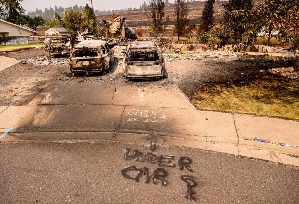 A note searching for a missing pet is painted on the street of a burned home during the Old Trails Fire in Spokane, Washington, August 4, 2026. (Josh Edelson / AFP)