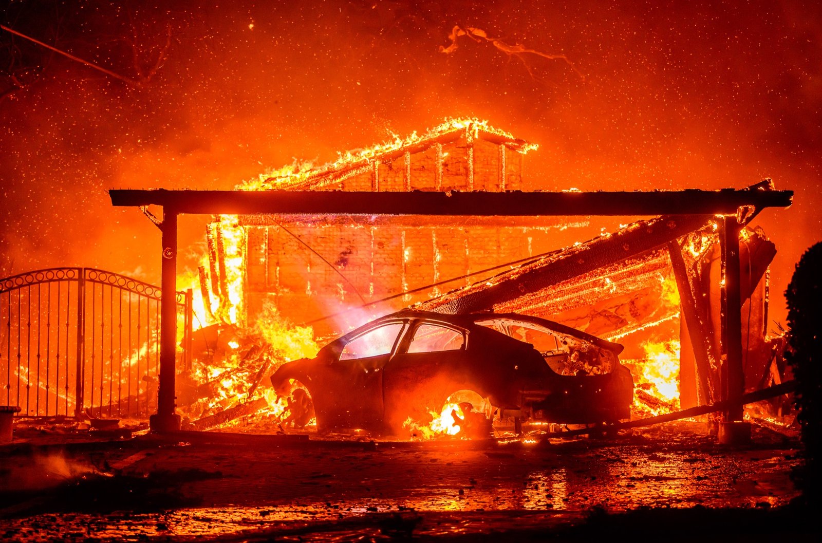A car and home burn during the Eaton fire in the Altadena area of Los Angeles County, California on January 08, 2025. Multiple fast-moving wildfires broke out in Los Angeles county burning buildings and causing thousands to evacuate as "life threatening" winds whipped the region. Frightened residents abandoned their cars on one of the only roads in and out of the upscale Pacific Palisades area, fleeing on foot from the 770-acre (310-hectare) blaze engulfing an area crammed with multi-million dollar homes in the Santa Monica Mountains. (Josh Edelson / AFP)