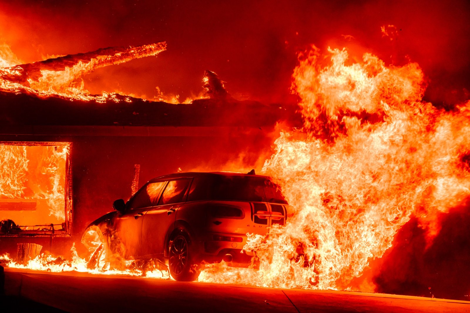 A car and home burn during the Eaton fire in the Altadena area of Los Angeles County, California on January 08, 2025. Multiple fast-moving wildfires broke out in Los Angeles county burning buildings and causing thousands to evacuate as "life threatening" winds whipped the region. Frightened residents abandoned their cars on one of the only roads in and out of the upscale Pacific Palisades area, fleeing on foot from the 770-acre (310-hectare) blaze engulfing an area crammed with multi-million dollar homes in the Santa Monica Mountains. (Josh Edelson / AFP)