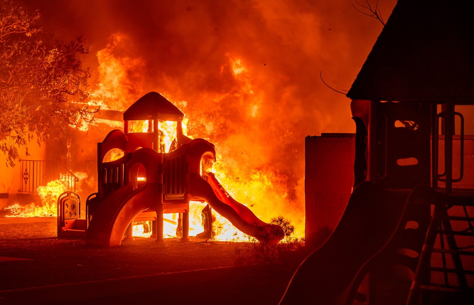 A playground burns in a residential neighborhood during the Eaton fire in Pasadena, California on January 07, 2025. Multiple fast-moving wildfires broke out in Los Angeles county burning buildings and causing thousands to evacuate as "life threatening" winds whipped the region. Frightened residents abandoned their cars on one of the only roads in and out of the upscale Pacific Palisades area, fleeing on foot from the 770-acre (310-hectare) blaze engulfing an area crammed with multi-million dollar homes in the Santa Monica Mountains. (Josh Edelson / AFP)