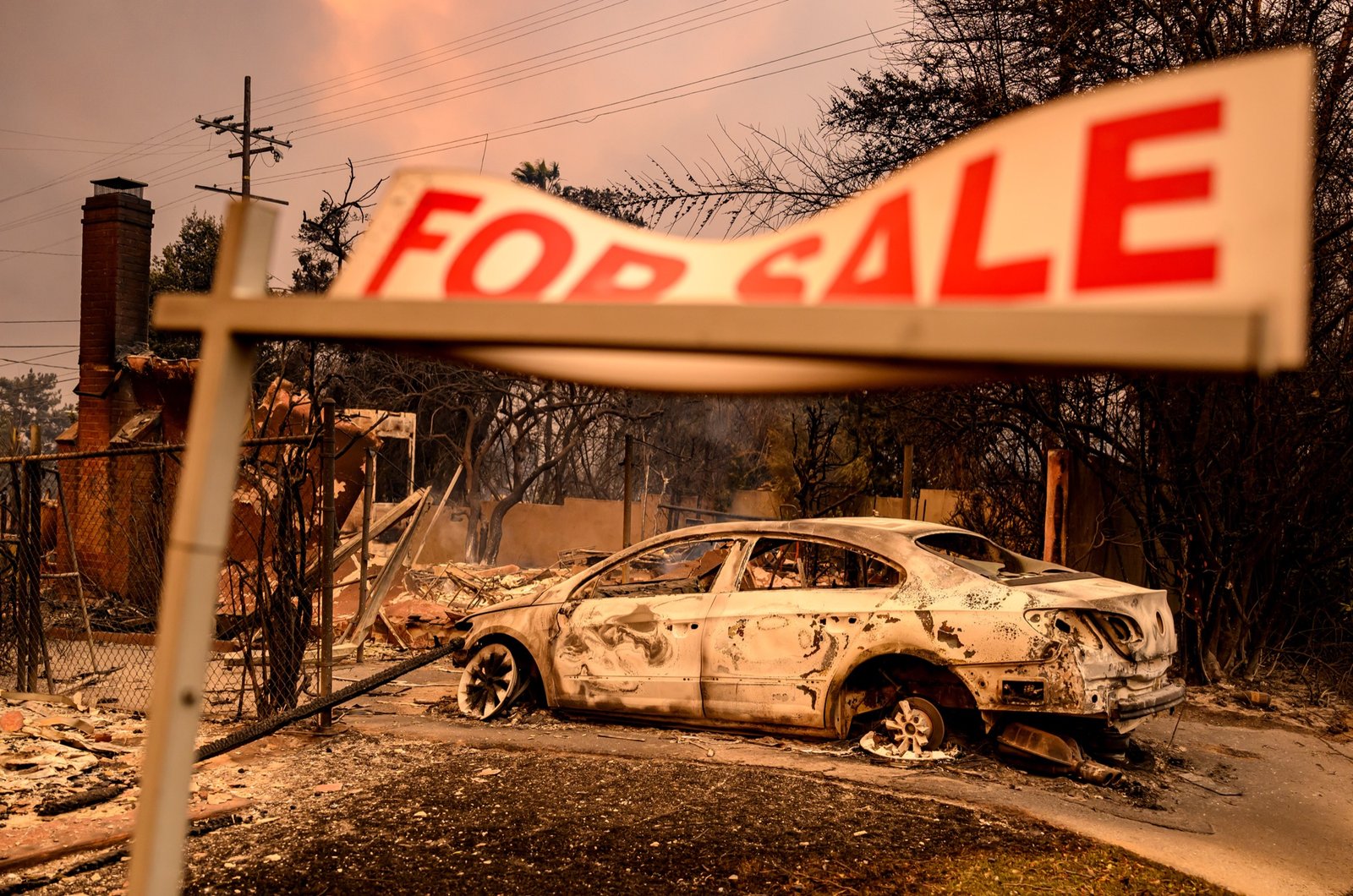 A for sale sign remains as homes smolder during the Eaton fire in the Altadena area of Los Angeles County, California on January 08, 2025. (Josh Edelson / AFP)