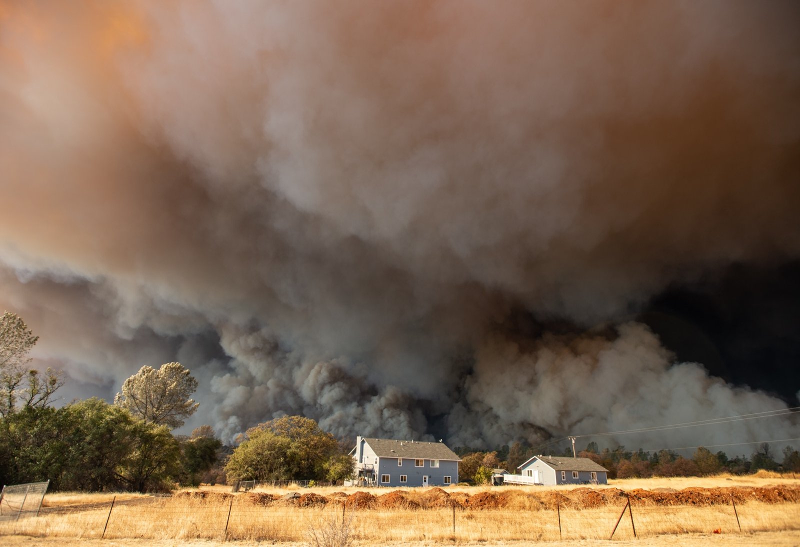 A home is overshadowed by towering smoke plumes as the Camp fire races through town in Paradise, California on November 08, 2018. More than 18,000 acres have been scorched in a matter of hours burning with it a hospital, a gas station and dozens of homes. (Josh Edelson / AFP)